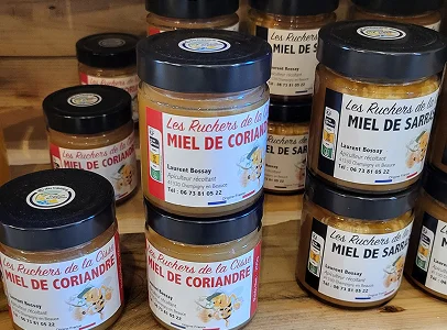 Différents pots de miel entreposés sur une étagère en bois